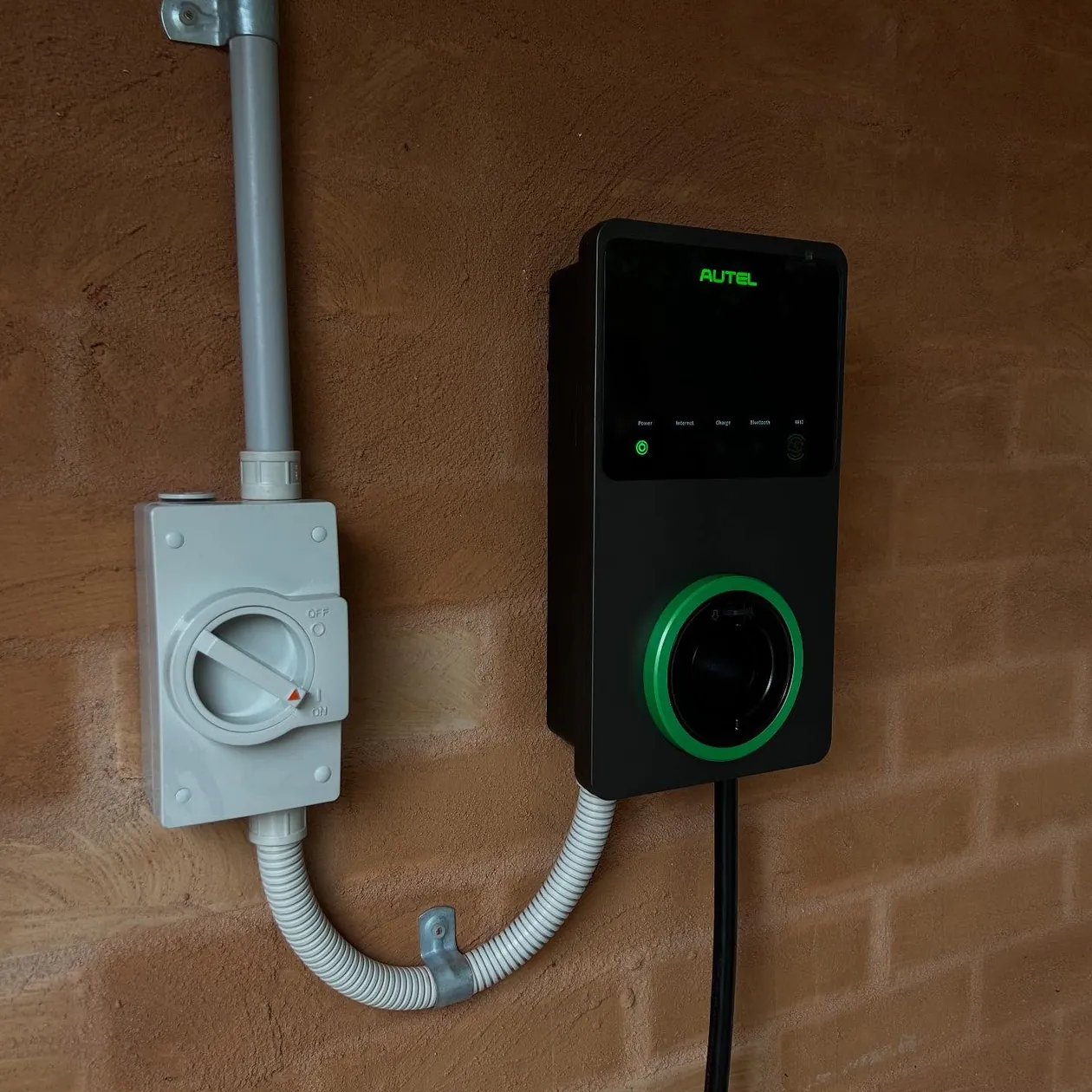 Wall-mounted EV charger and isolator installed on a brick wall